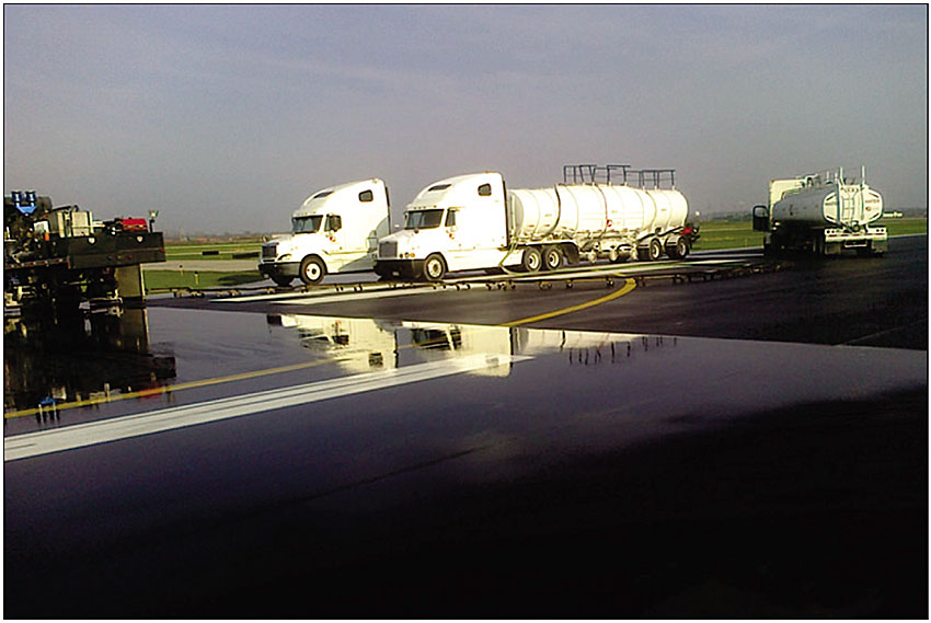 Photo 7. A grooved runway (the section where the trucks are parked) versus a non-grooved runway, shown after being flushed with water during the grooving process (photo used with permission from the St. Louis Downtown Airport [KCPS])