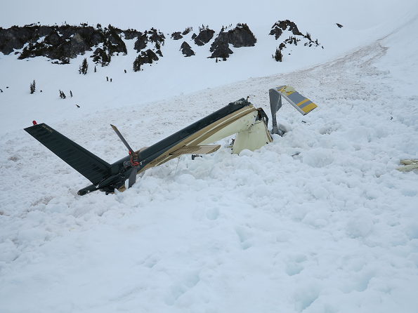 Le rotor et la queue de l'hélicoptère écrasé, qui dépassent de la neige du flanc de montagne